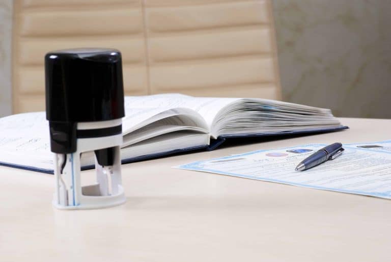 Desk with stamp, documents, and open book.