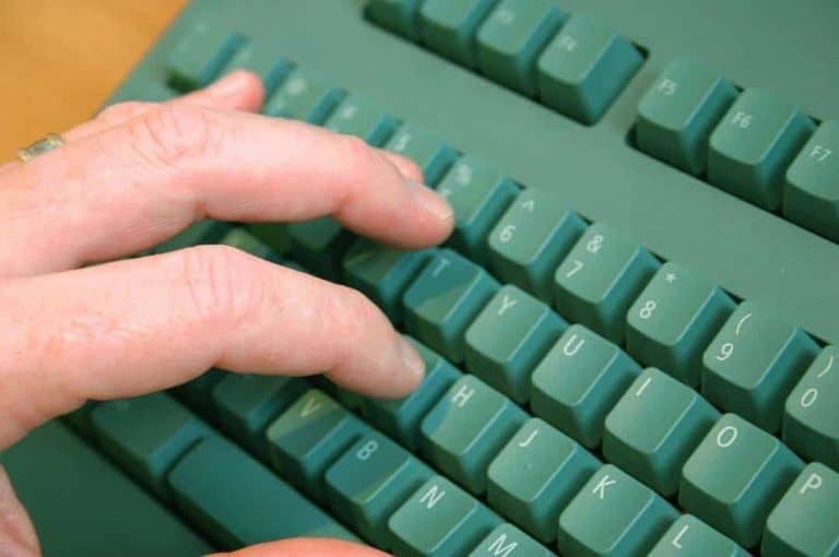 Fingers typing on green computer keyboard.