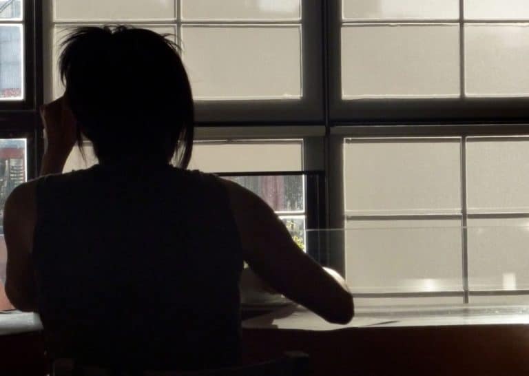 Silhouette of person sitting by a window